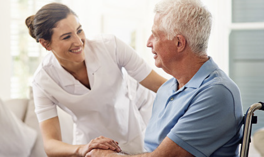 Elderly man receiving care and comfort from a young nurse with brown hair