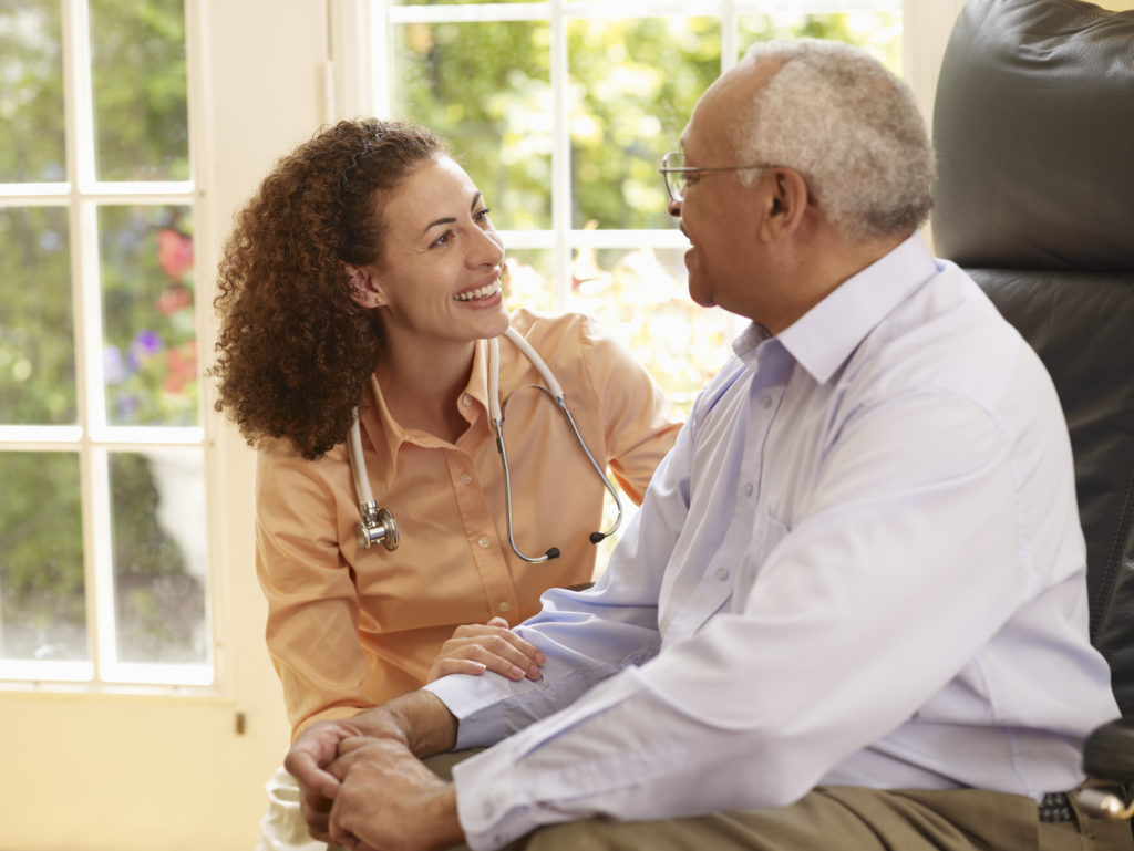 Picture of an elderly black patient meeting with a young black doctor wearing a stethoscope