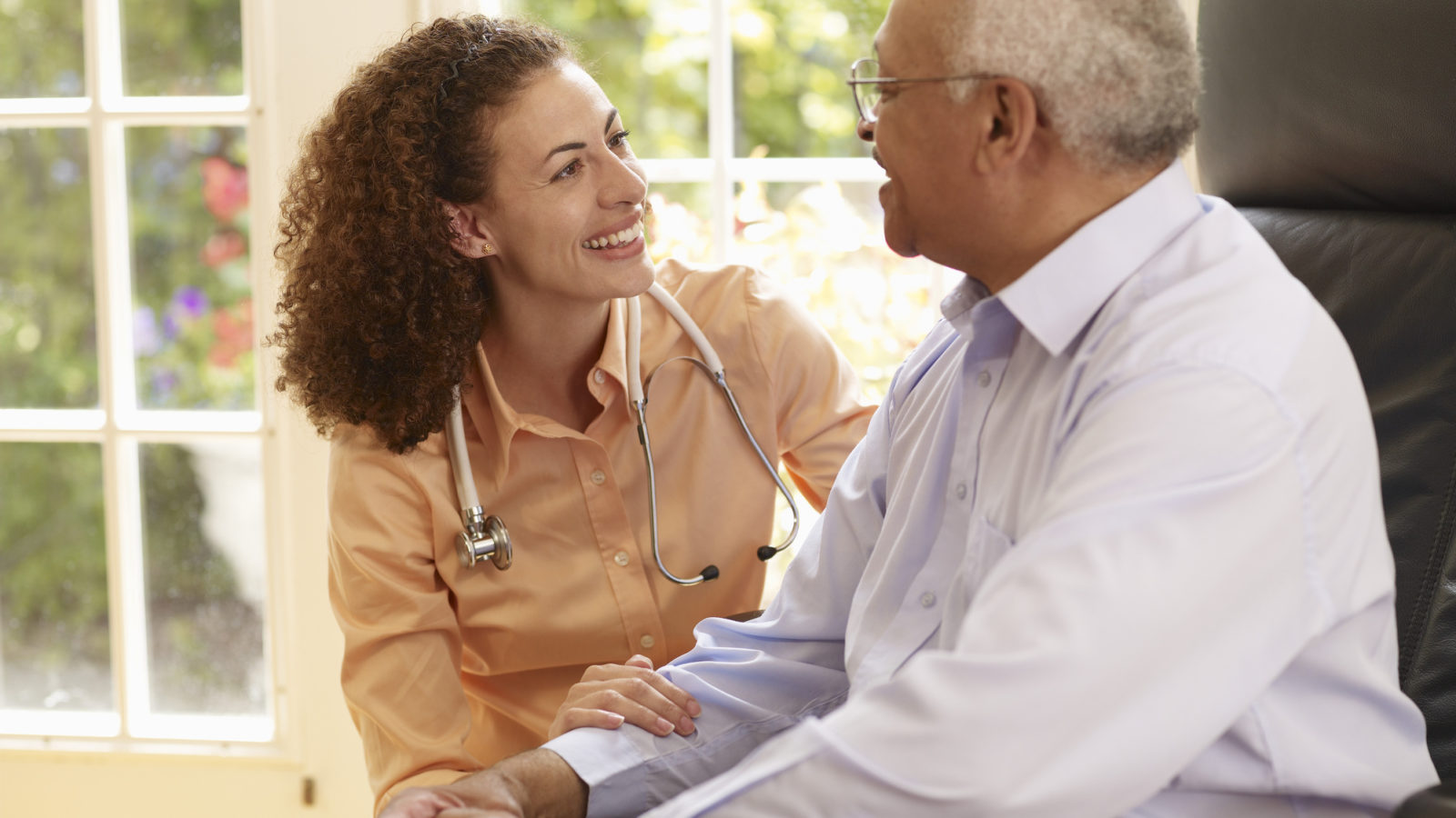 Picture of an elderly black patient meeting with a young black doctor wearing a stethoscope