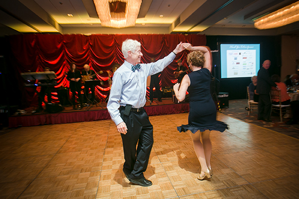 Well dressed doctor twirling female dance partner on dance floor at Hope Hospice Gala