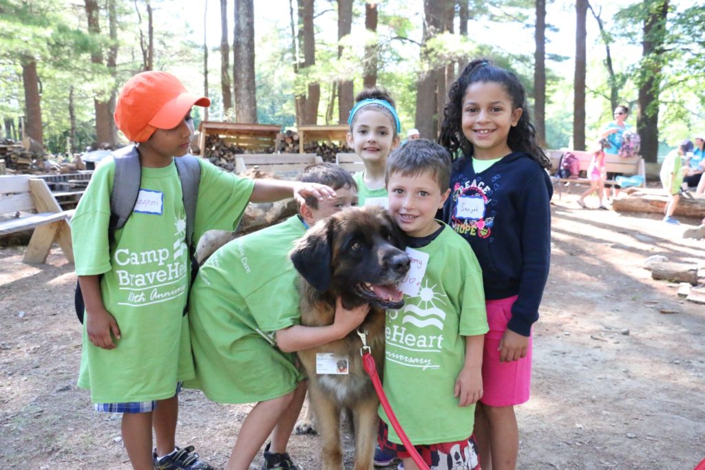 Five Children in green Camp Braveheart shirts petting and hugging a dog