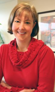 Woman in red sweater smiling with arms crossed in front of her. She explains: what is palliative care?