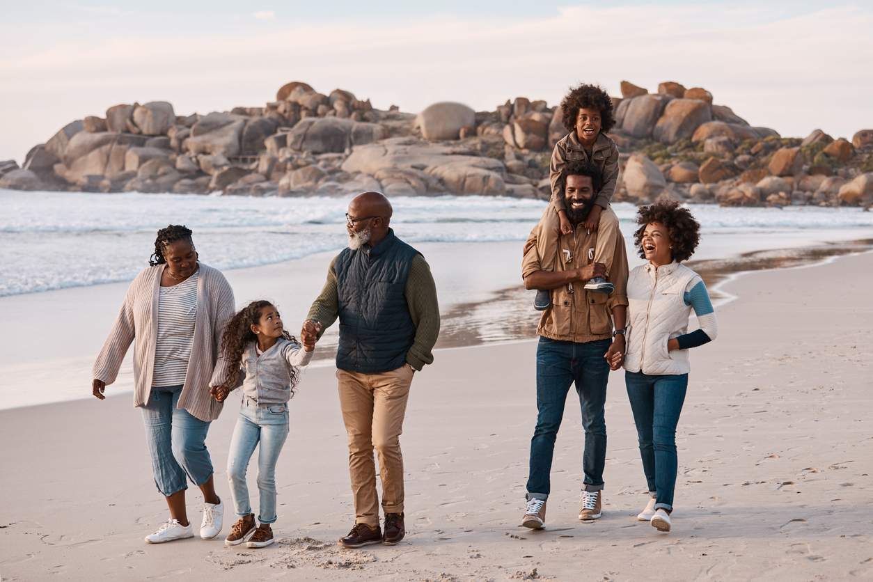 Multigenerational family on the beach. The grandfather is able to enjoy time with family because his symptoms are managed by palliative care.