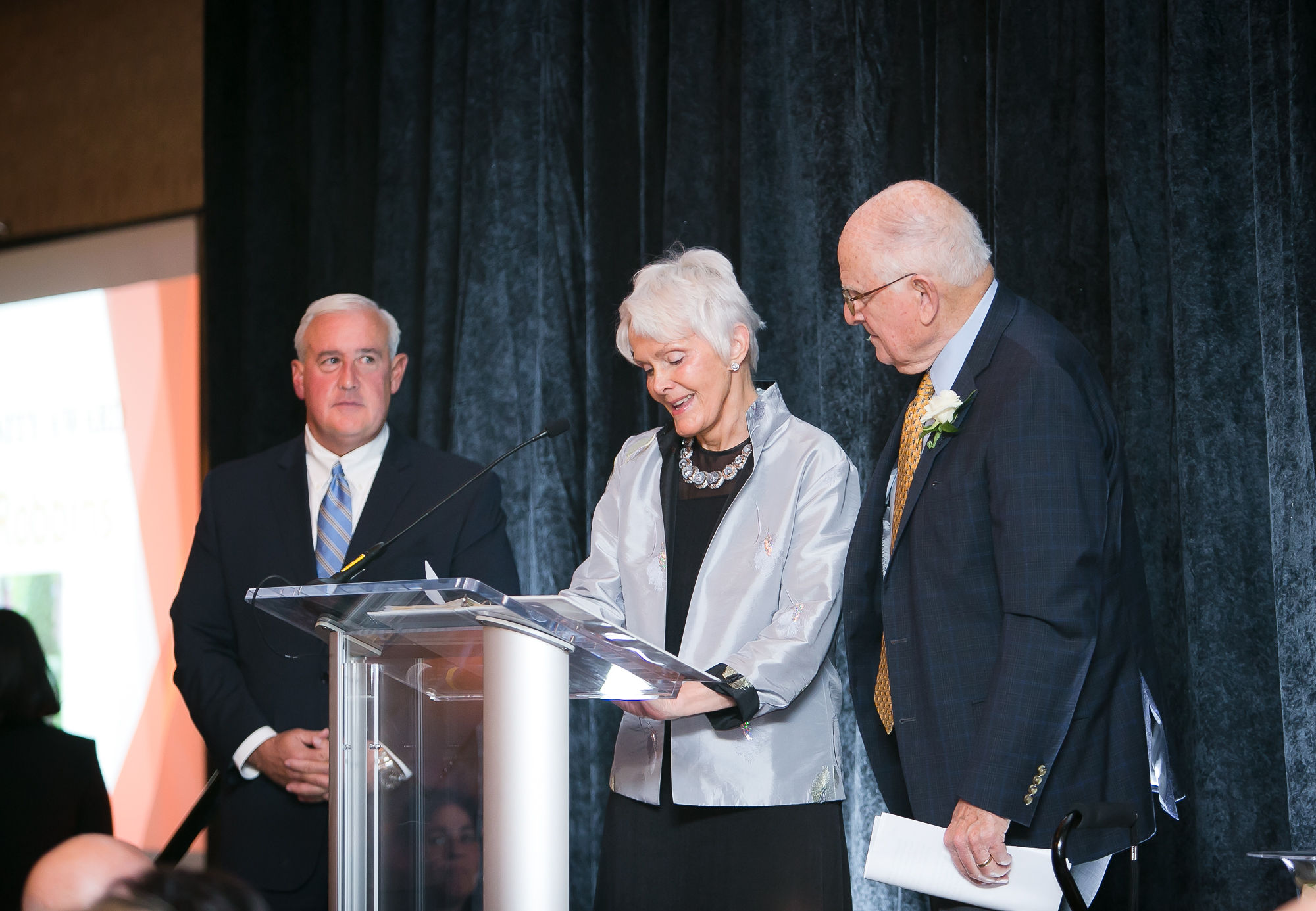 Arthur Robbins receives the Human Dignity Award. Woman speaks at podium as two men stand on either side of her