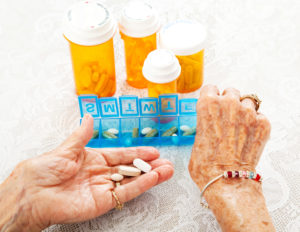 Closeup view of an eighty year old senior woman's hands as she sorts her prescription medicine.