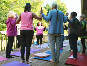 A group of people doing yoga poses in a circle and touching palms