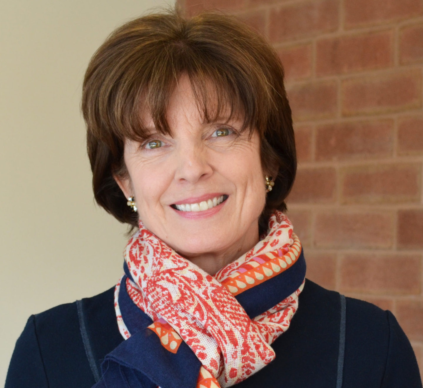 Woman smiling with a bright navy blue and red scarf around her neck