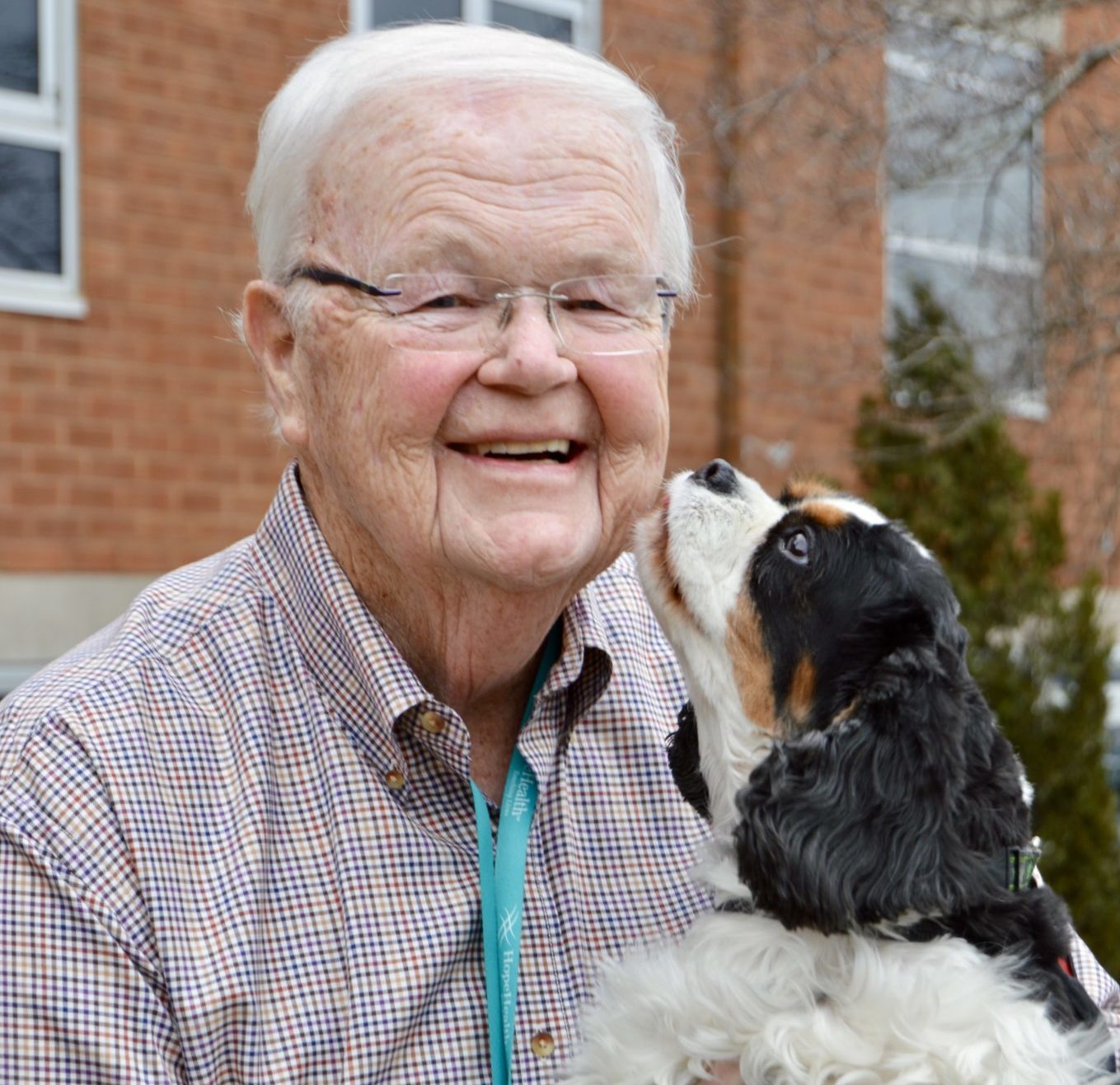 King Charles Spaniel licks the face of an elderly man