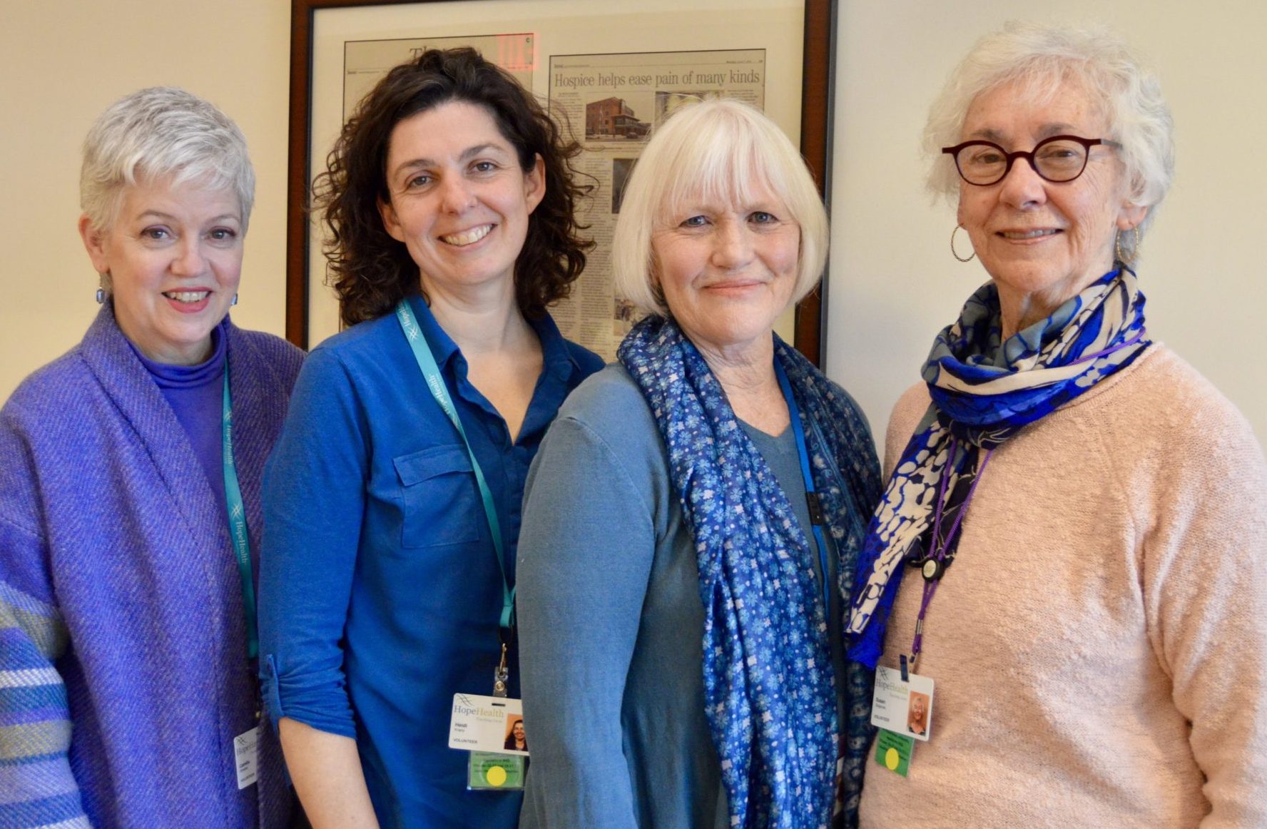 Four women stand smiling in front of a painting