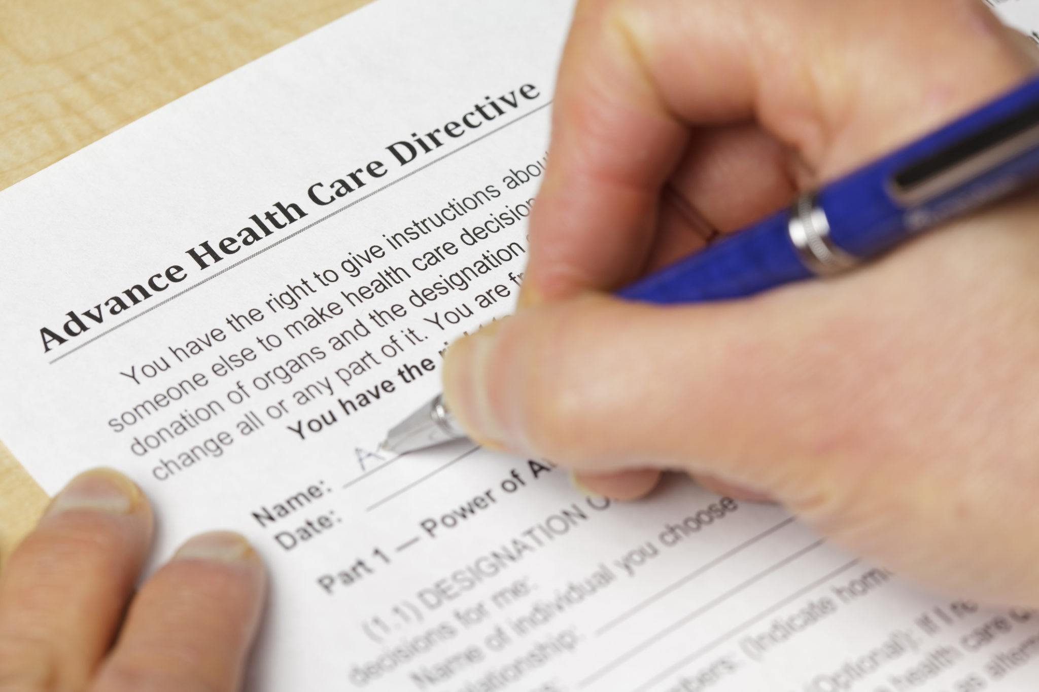 A person filling out a form titled Advance Health Care Directive and a pen. Notes: Very shallow focus on the word 'Health". Form created for photo using text in public domain.