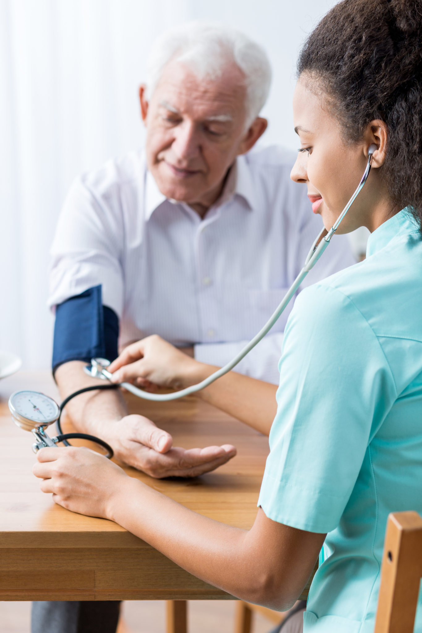 You've got too high blood pressure Carer taking senior's blood pressure, sitting beside table.