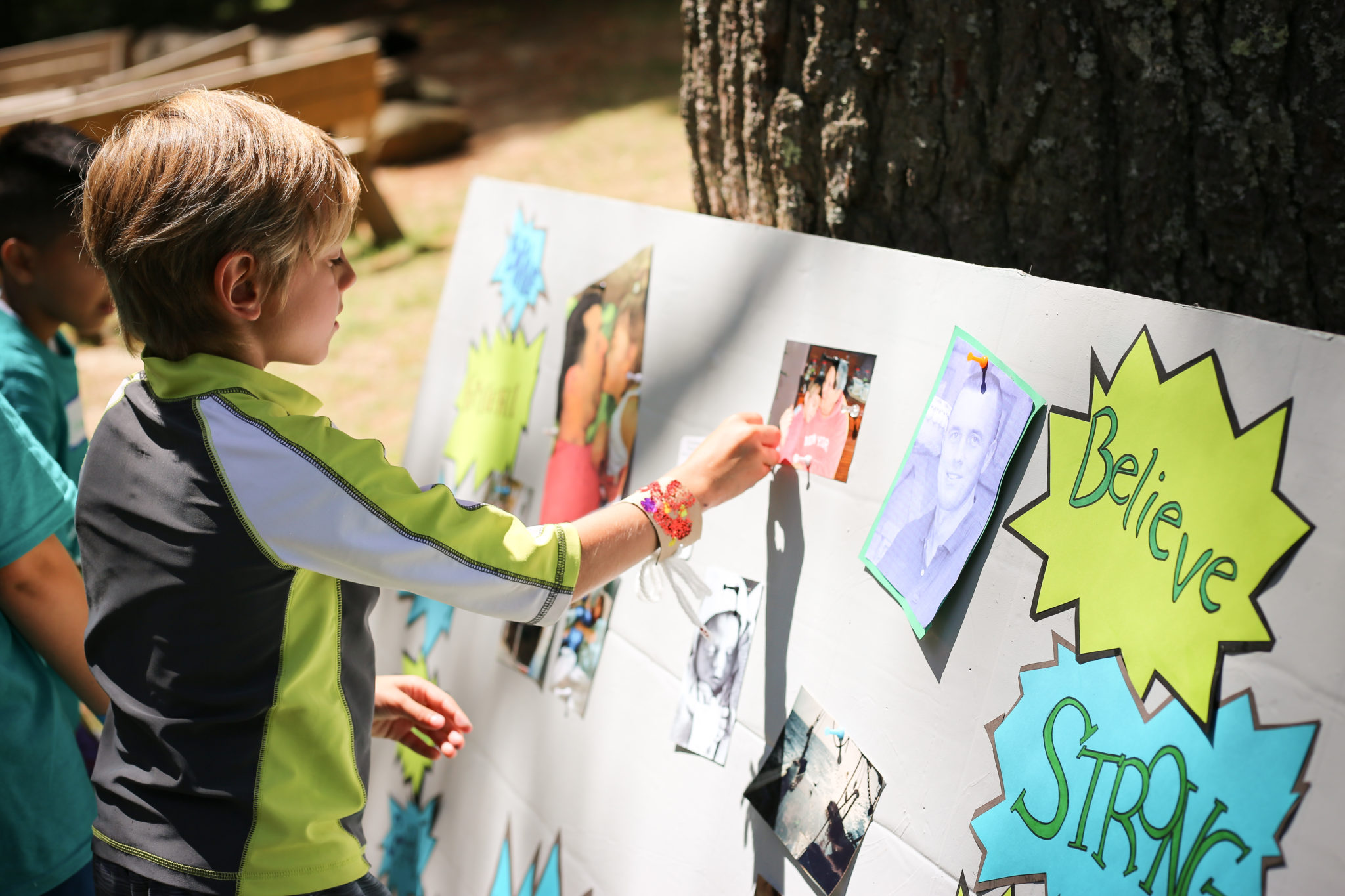 young boy pinnig a photo on a memory board