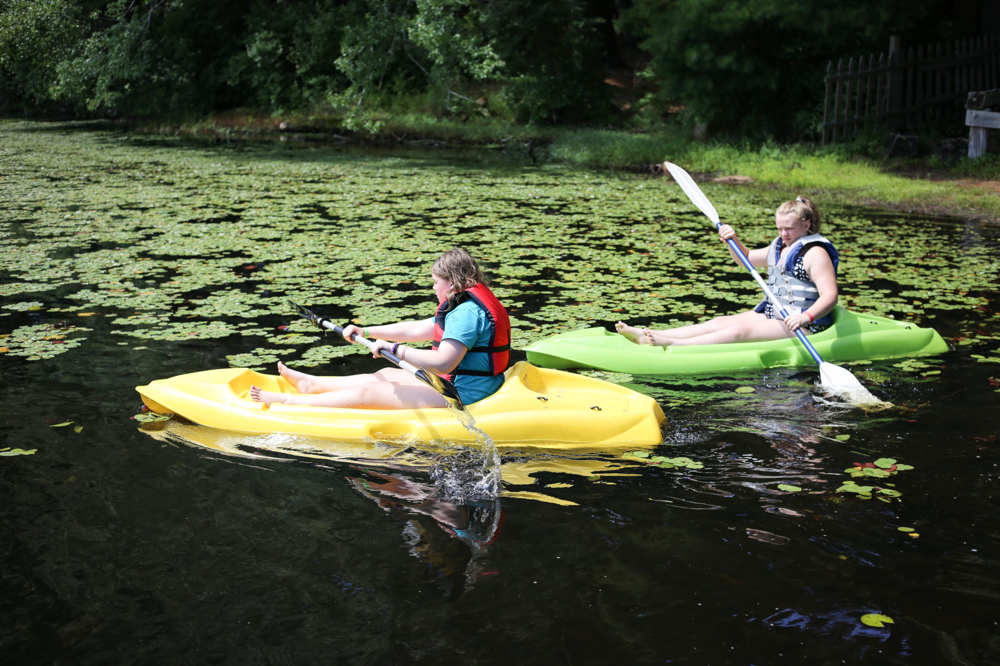 IMG_9291 children in a yellow and green kayak on the water near lilly pads