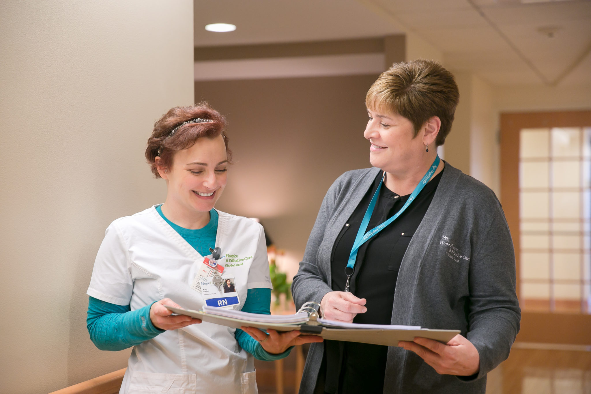 Two nurses smiling while reviewing a patient's chart