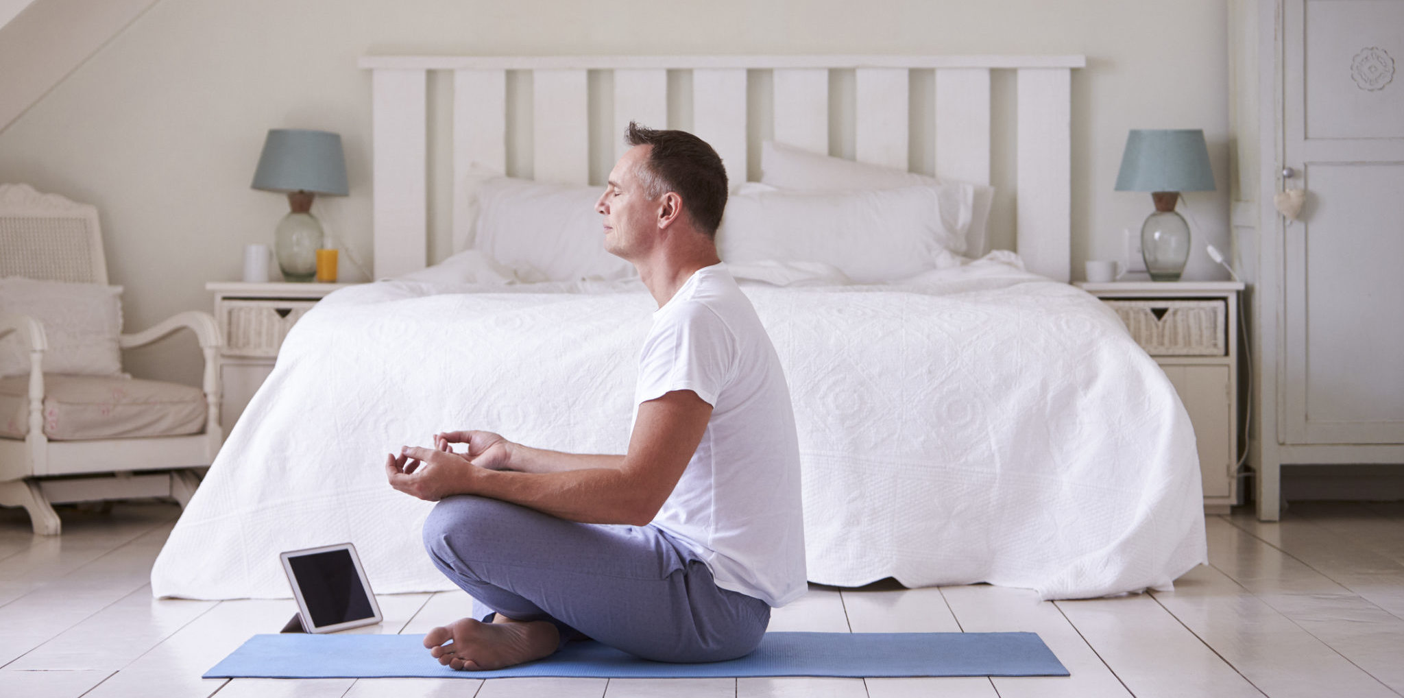 Mature Man With Digital Tablet Using Meditation App In Bedroom