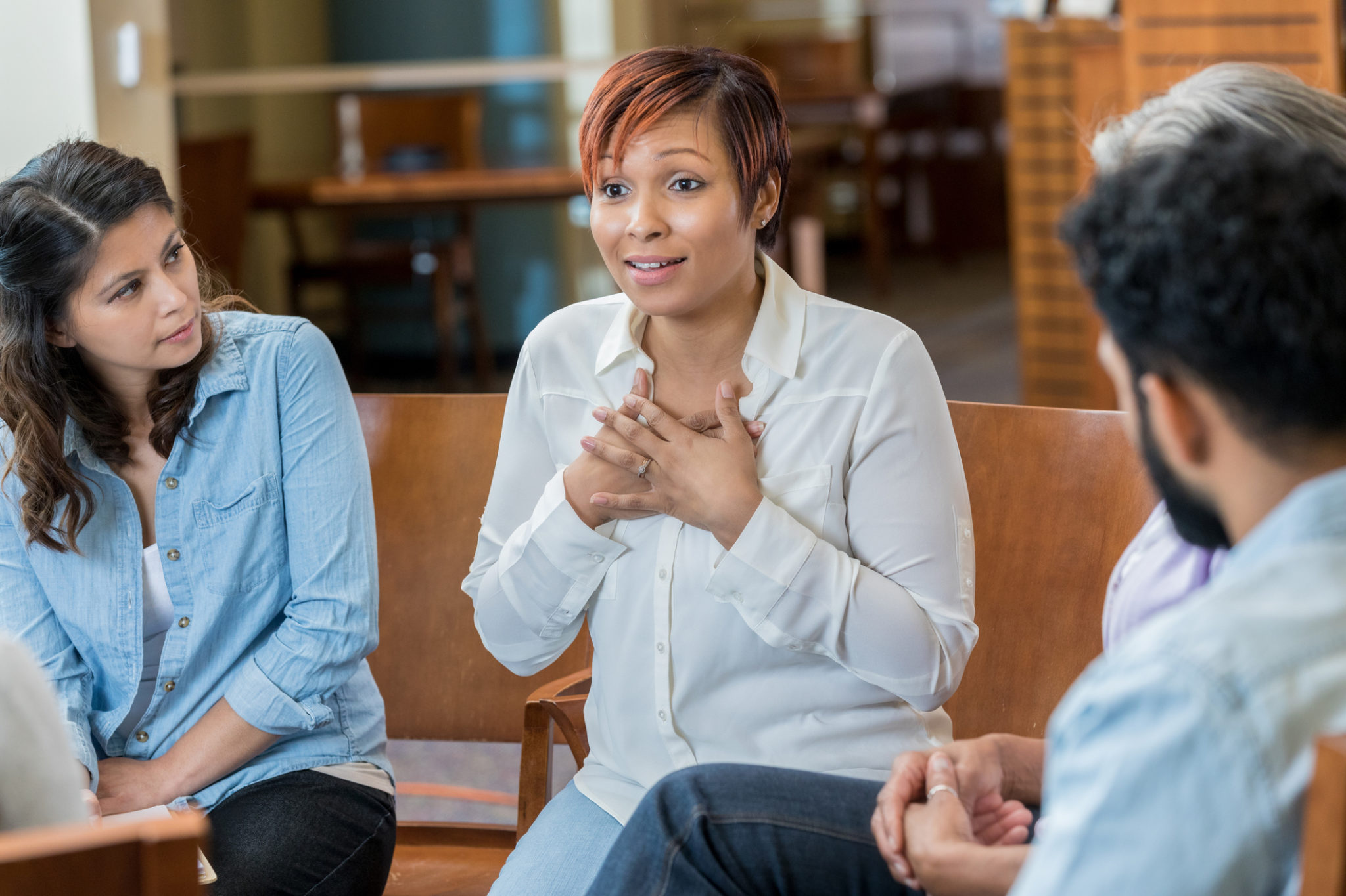 Serious woman discusses something difficult during a support group meeting.