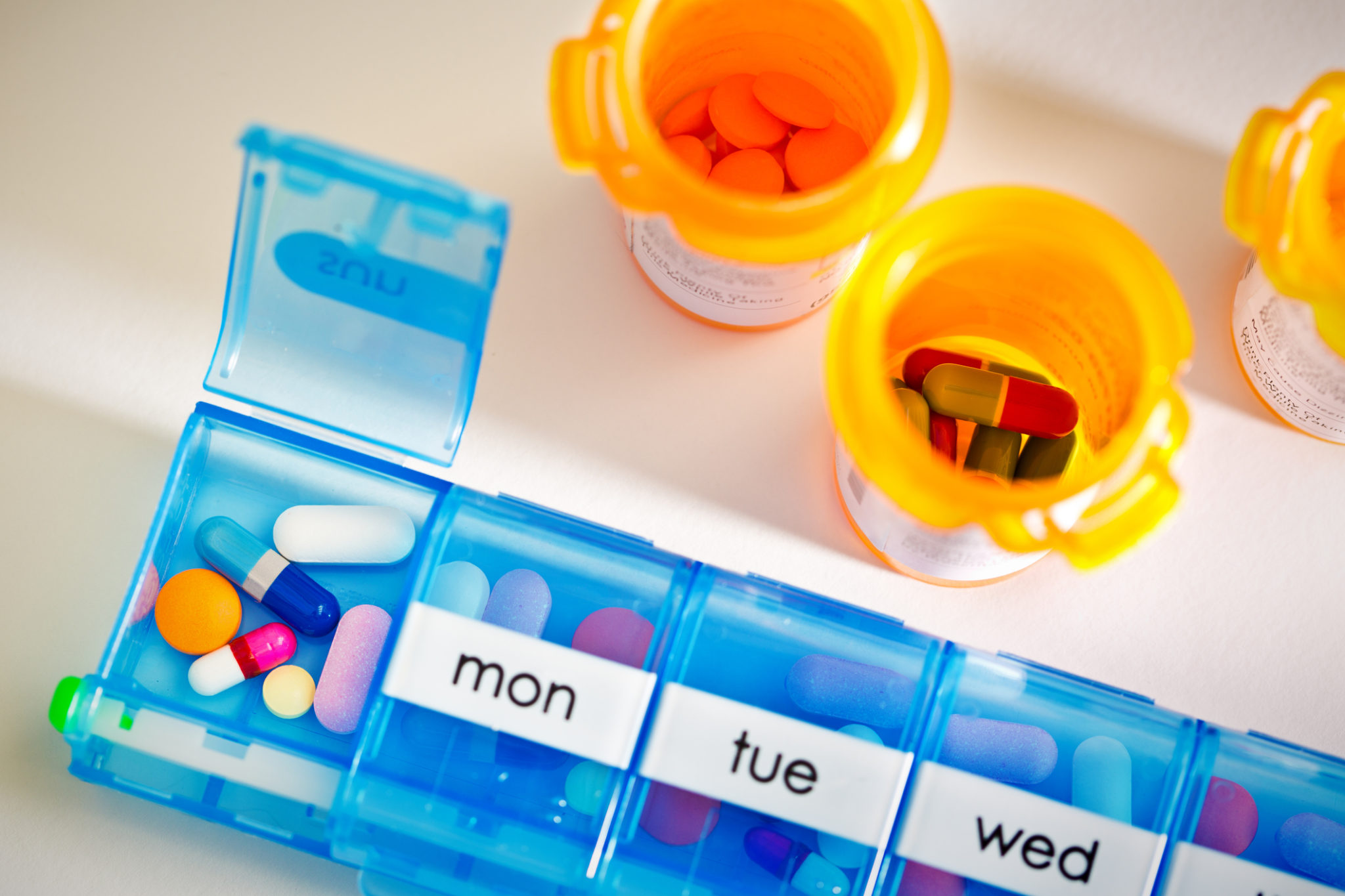 A medication pill box daily chamber filled with a variety of prescription drug. concept still life of medicine in healthcare, opioid social issue, and prescription drug abuse.