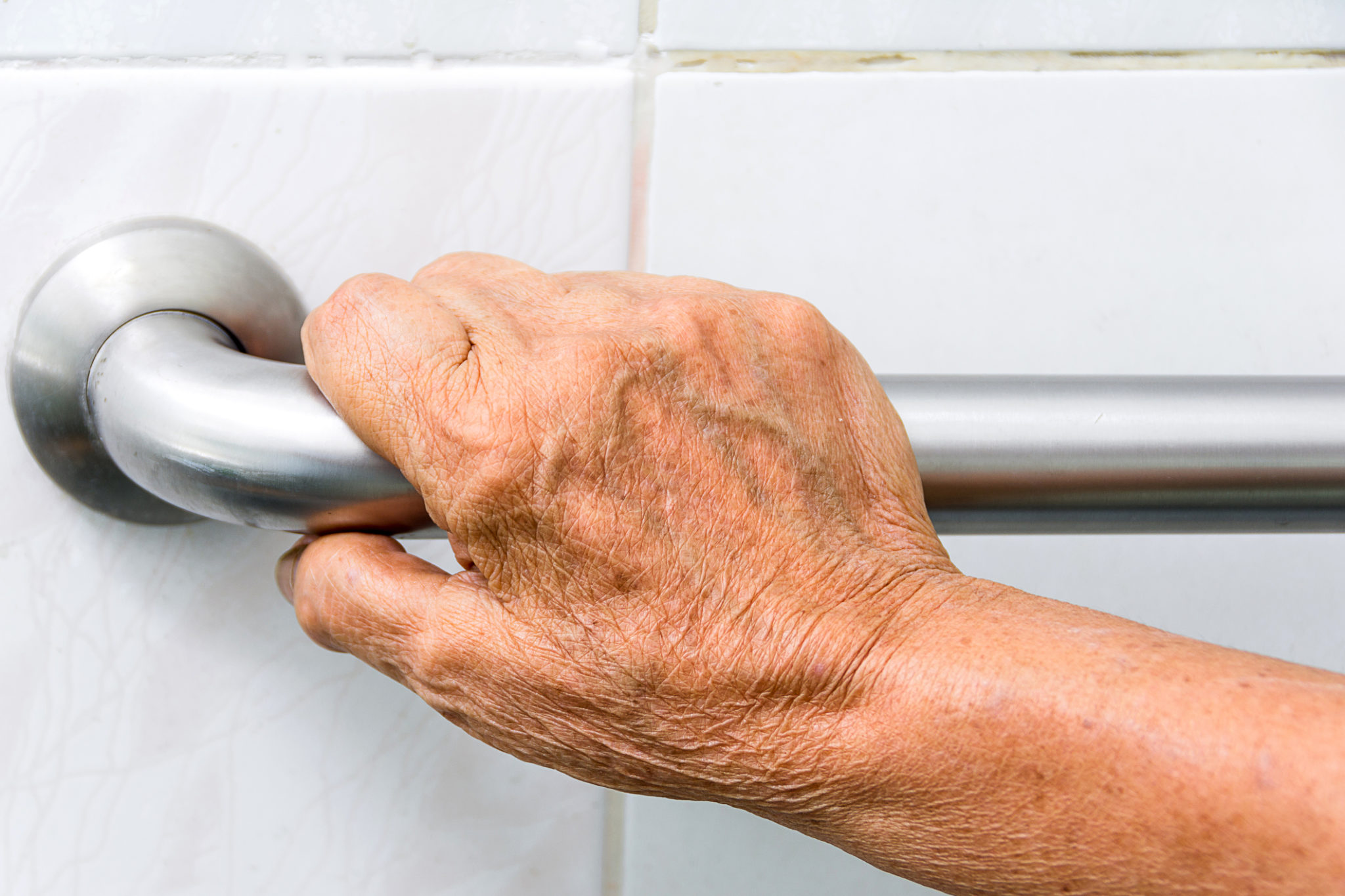 elderly holding a grab bars in a bathroom