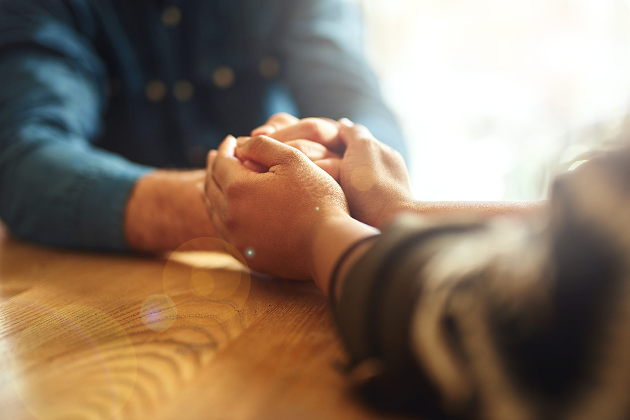 Cropped shot of two people holding hands in comfort