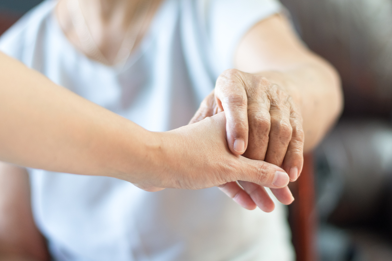 Elderly female hand holding hand of young caregiver at nursing home.Geriatric doctor or geriatrician concept. Doctor physician hand on happy elderly senior patient to comfort in hospital examination