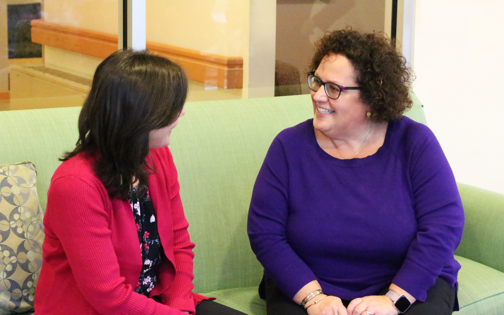 Two women smiling on a couch together