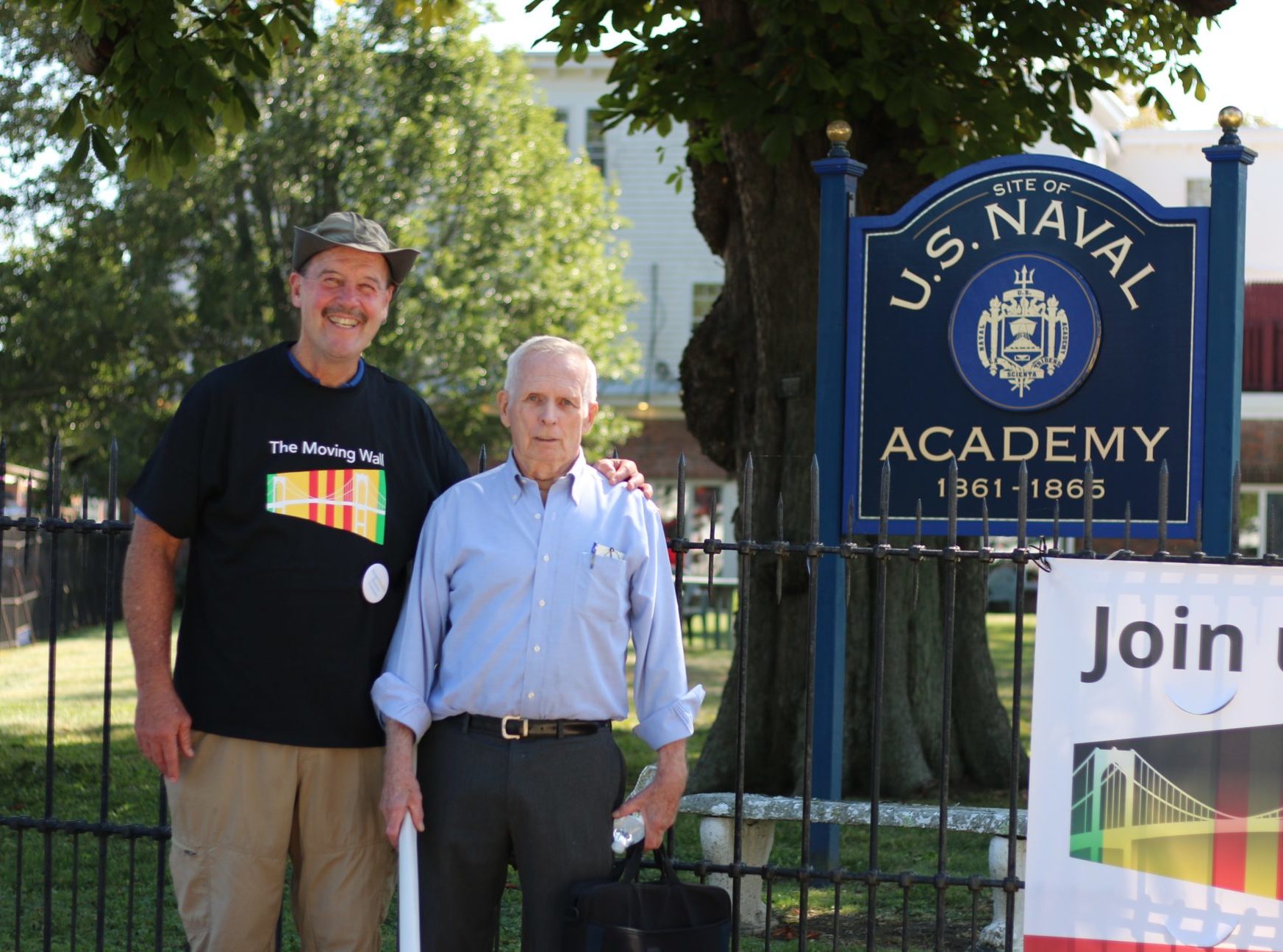 Two men standing in front of US Navy Academy