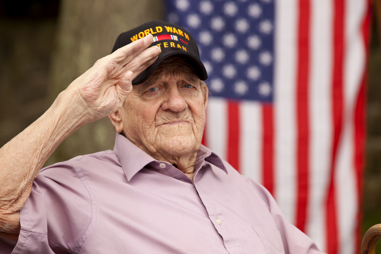 Hand salute and looking directly in to camera with concerned look on his face, with US flag in background. Image shot with Canon 5D Mark2, EF 70-200 f2.8L USM lens, natural light.