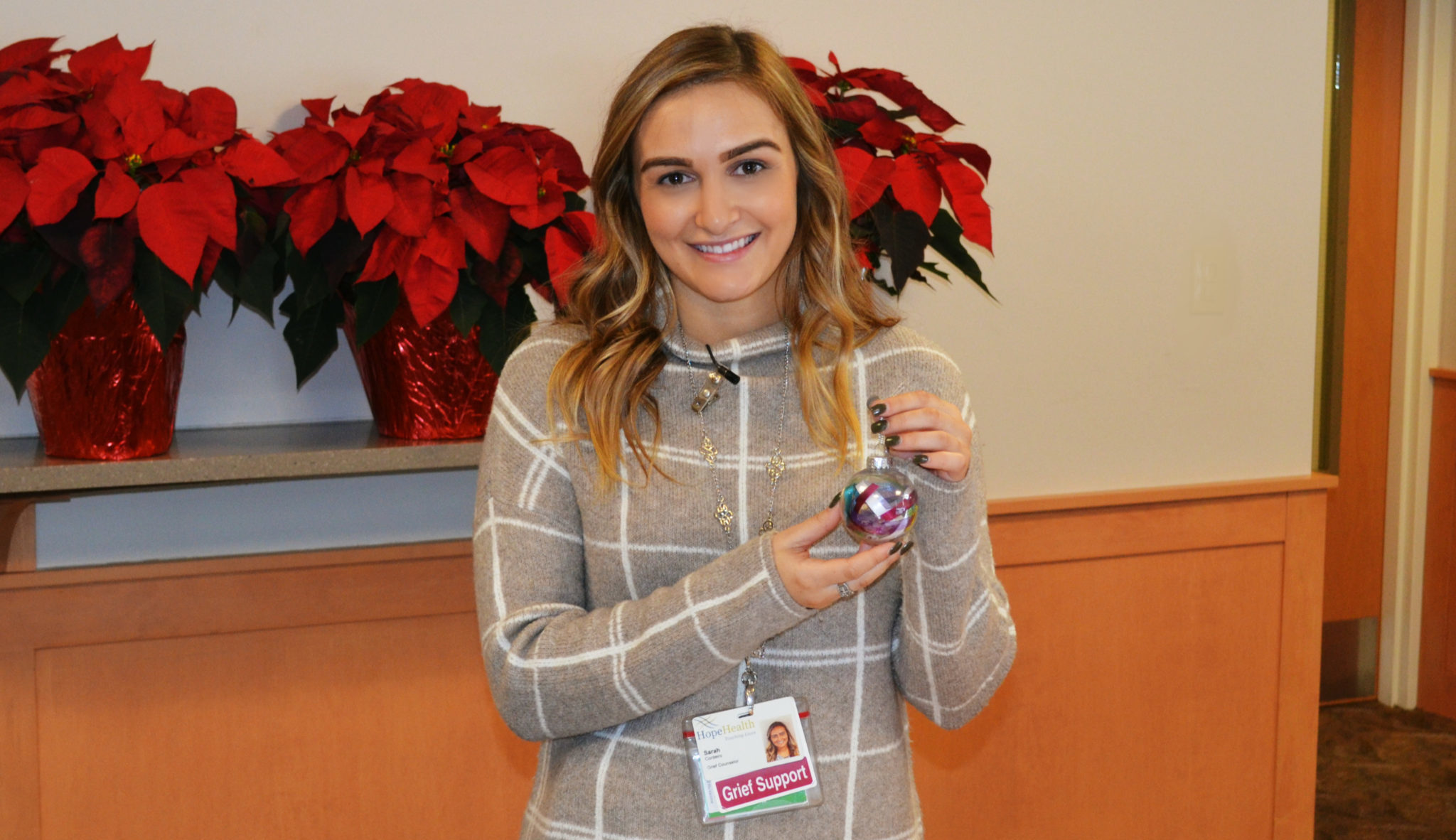 Young woman smiling with holiday remembrance ornament in her hand