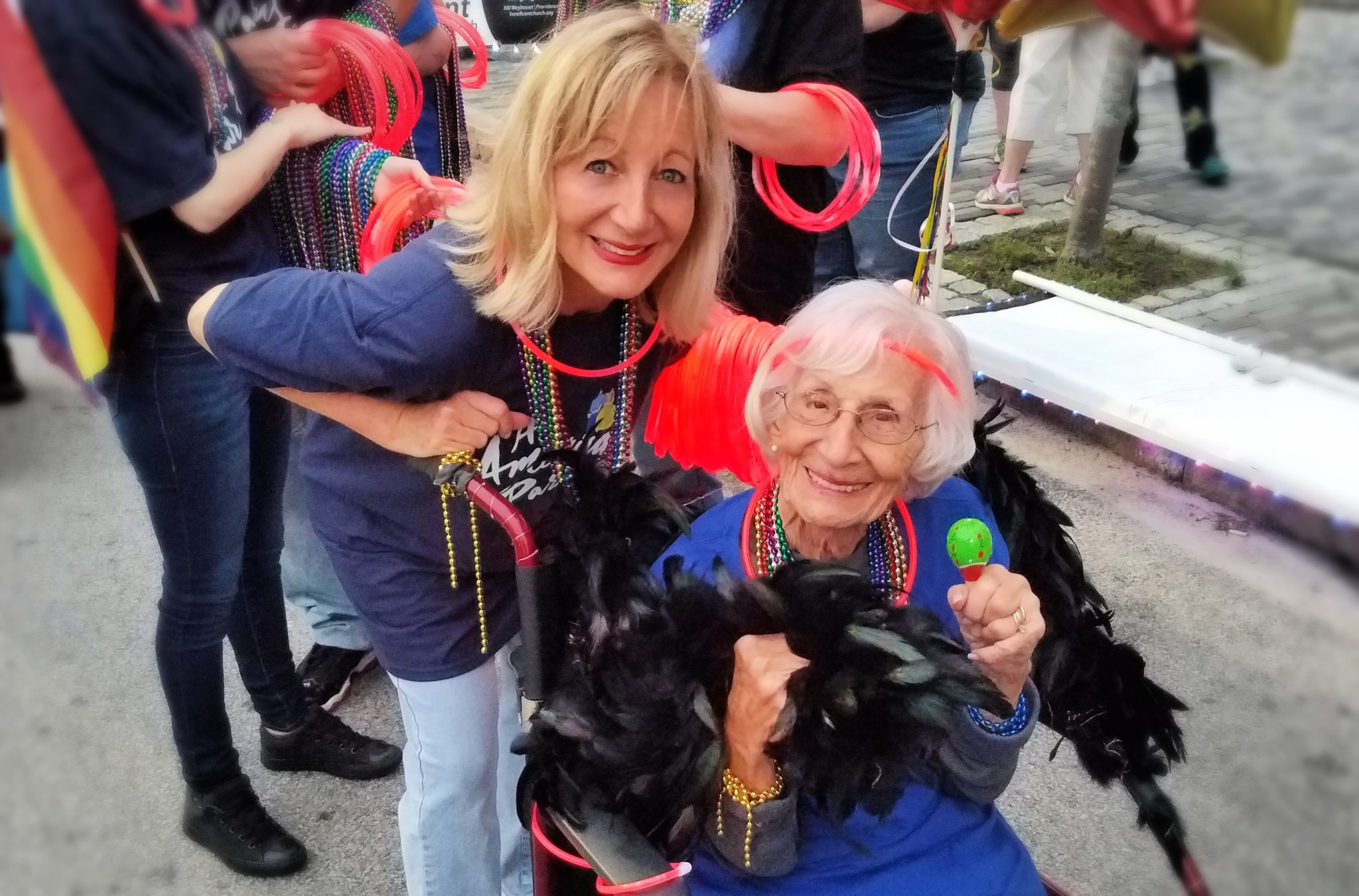 Blonde daughter pushing her elderly mom in her wheelchair at a parade