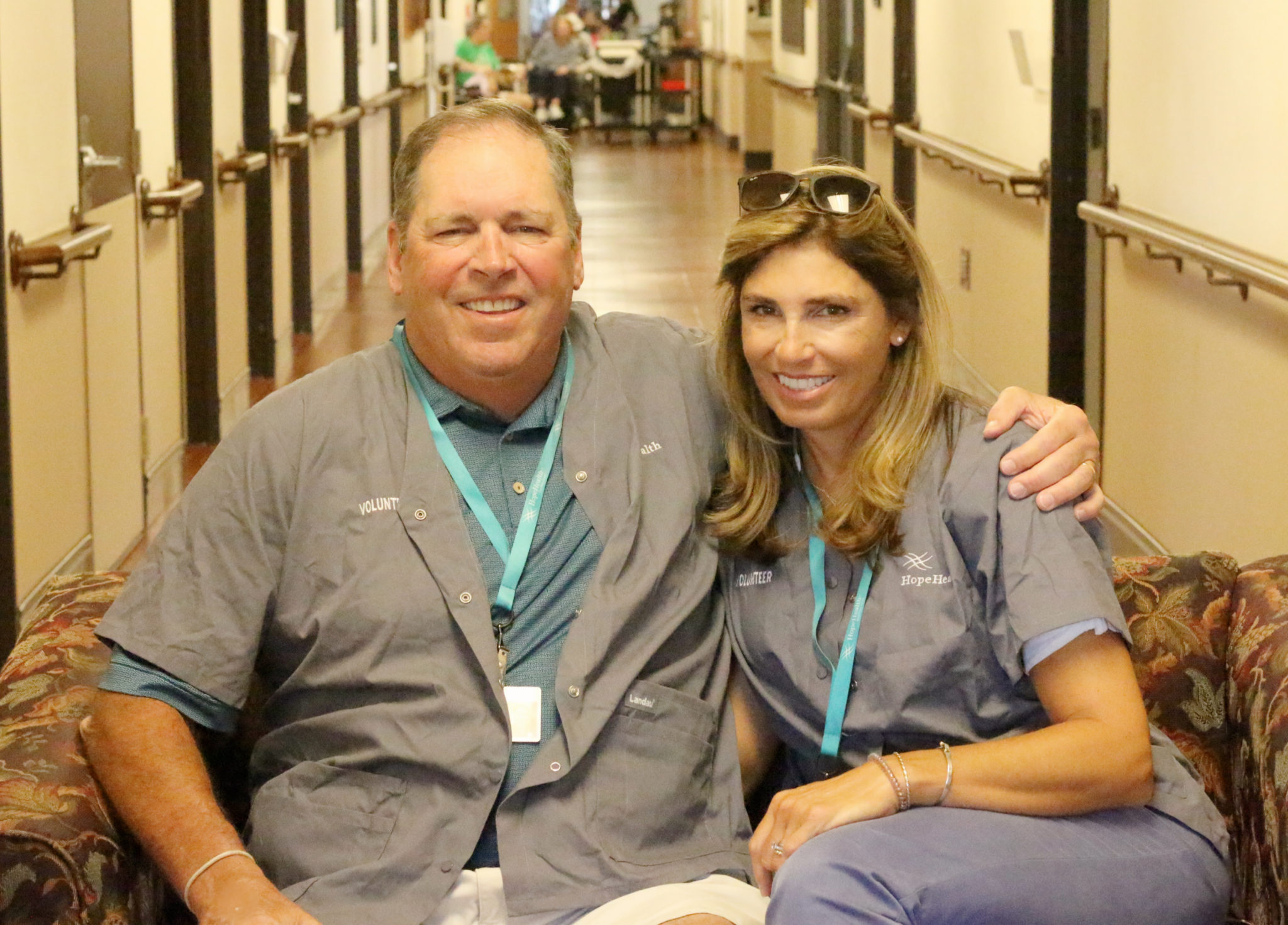 Husband and wife sit on a couch at a nursing home in Attleboro, Massachusetts where they are hospice volunteers