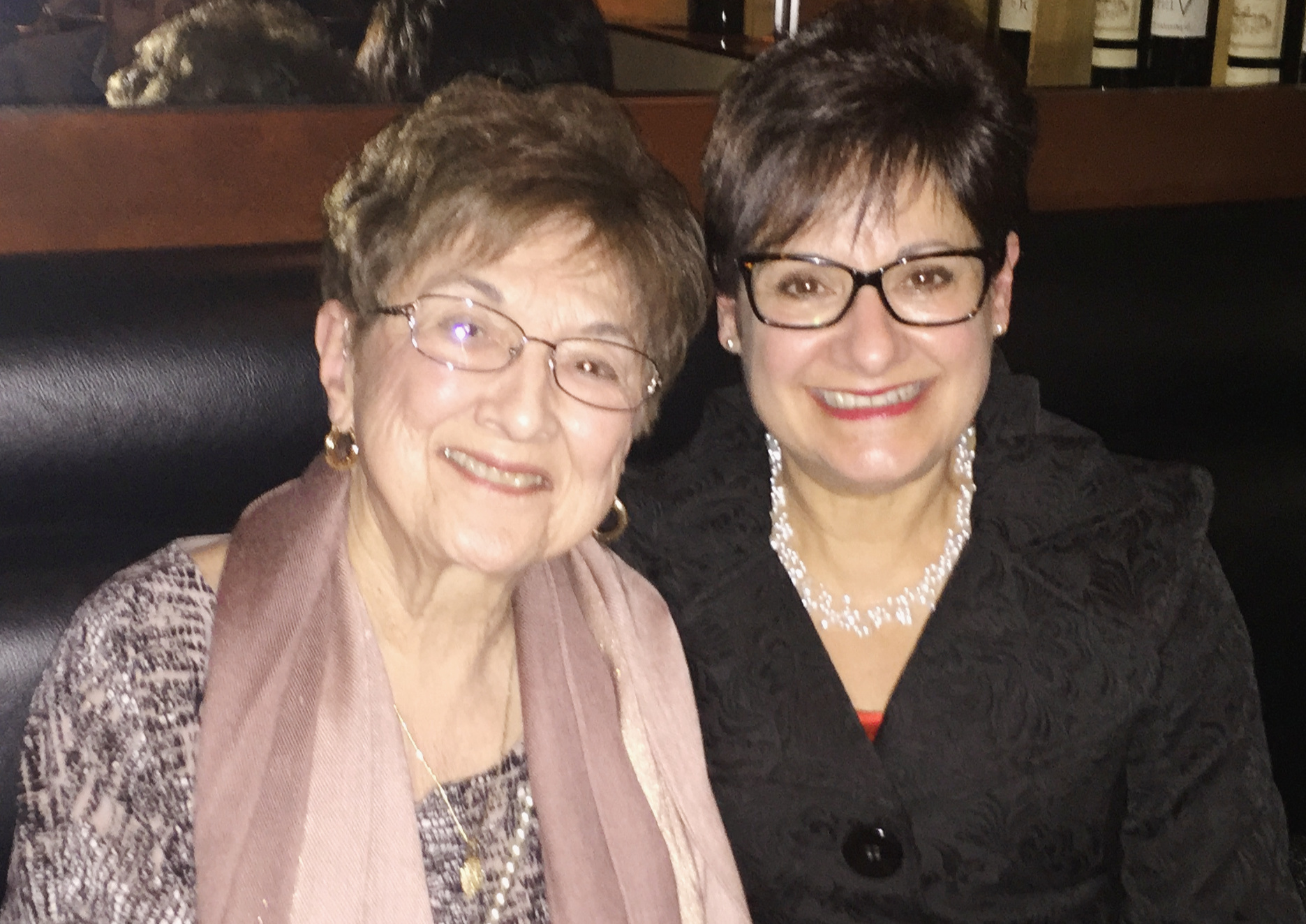 Mom wearing a pink scarf and glasses with her daughter wearing a black shirt and glasses