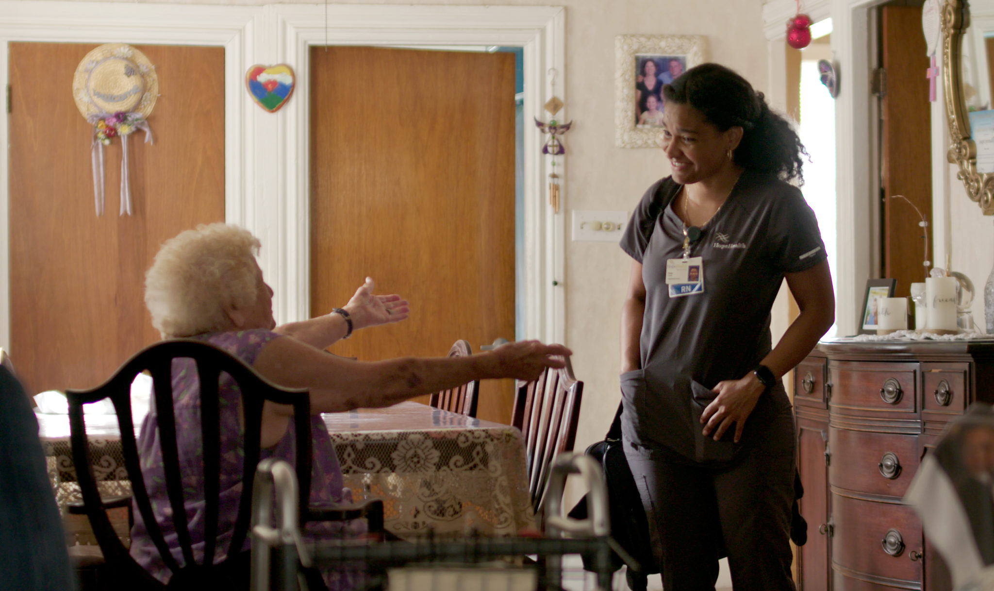 Elderly patient reaching out to hug her home care nurse