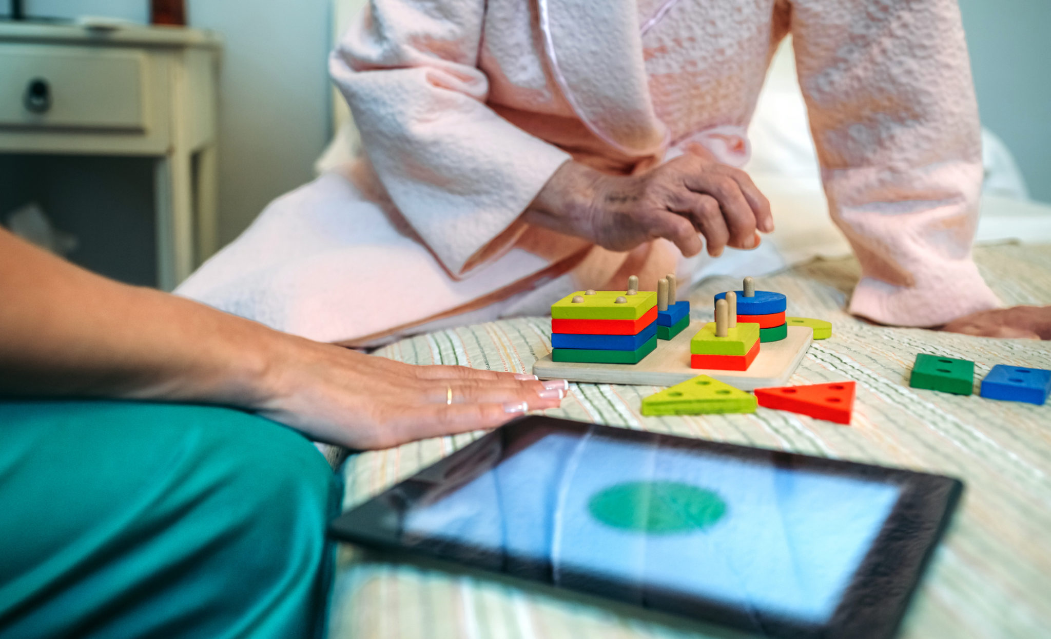 Female doctor showing geometric shapes to elderly patient Female doctor showing geometric shape game to elderly female patient with dementia