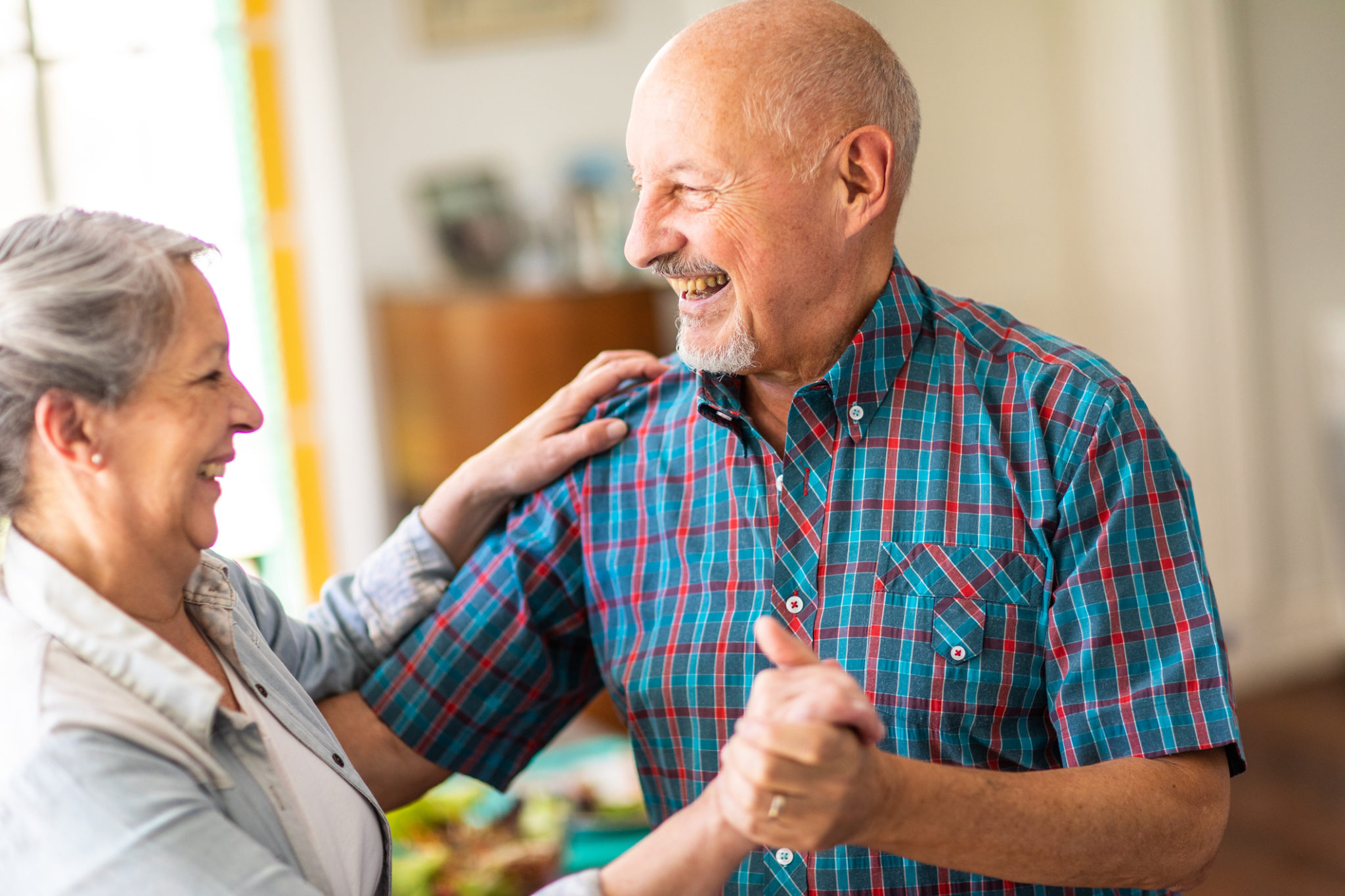 They find a special moment in every day Argentinian, married, elderly couple dancing, smiling and looking each other at home