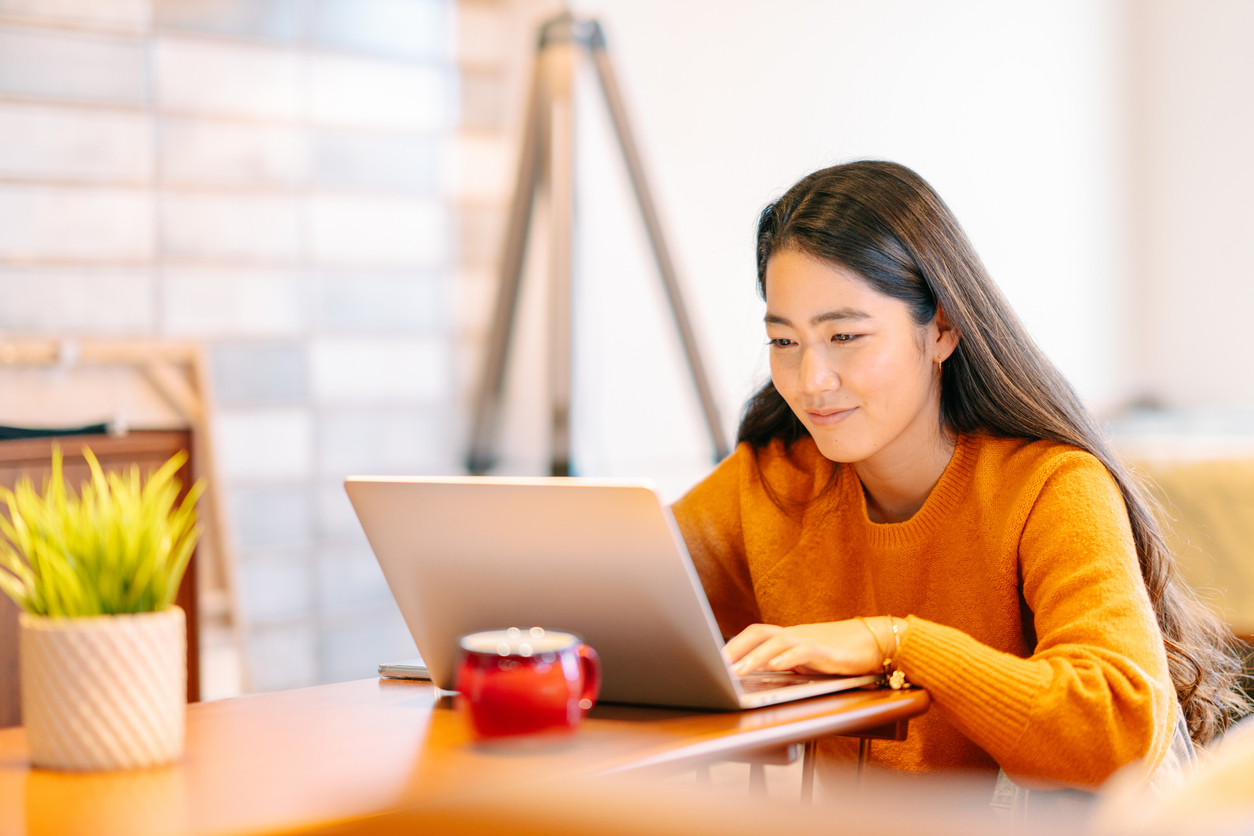 A young woman is using a laptop comfortably in the living room at home.