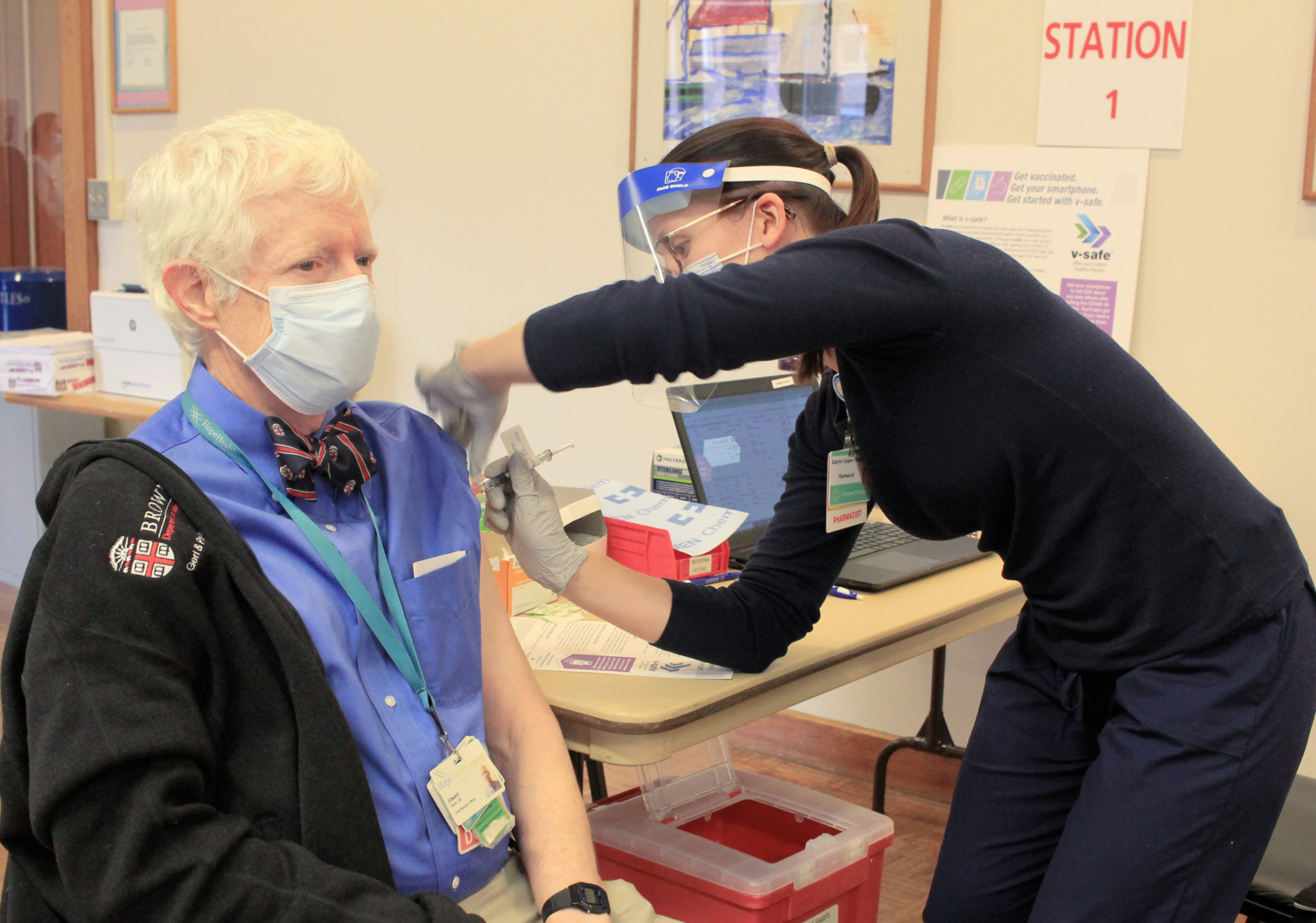 Man with white hair in a medical mask is receiving the COVID-19 vaccine