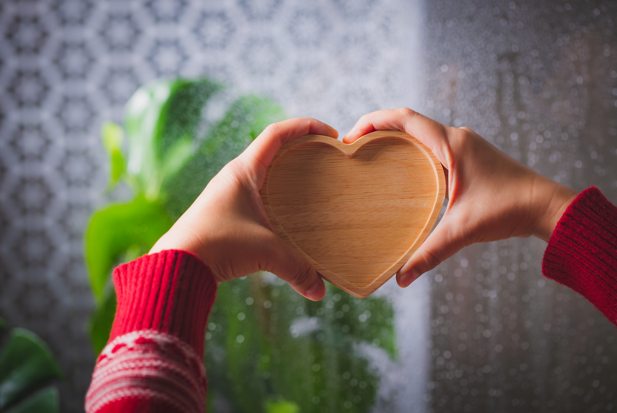Woman hand holding wooden heart on rainy background, Valentine day concept