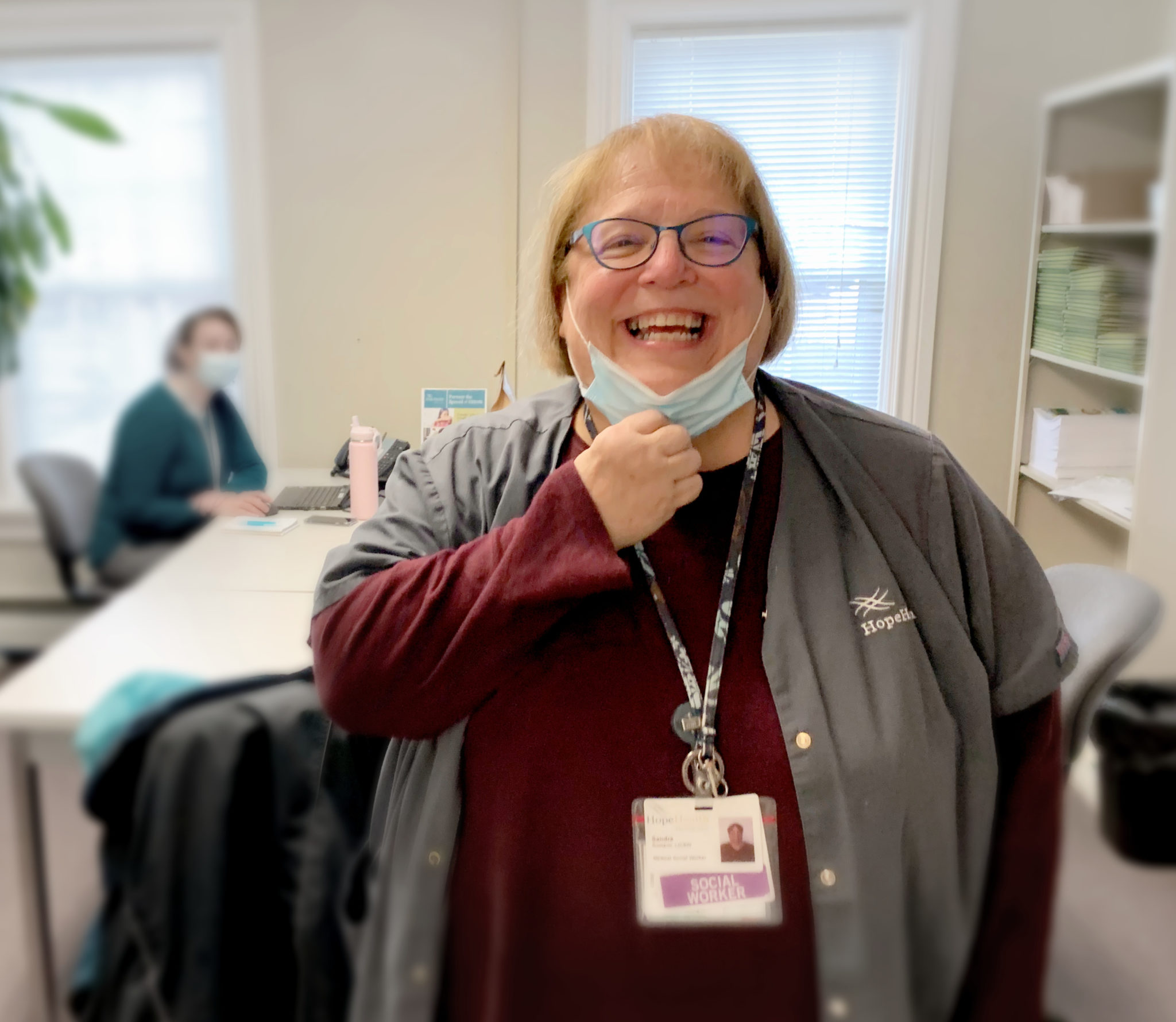 Hospice social worker pulls down her surgical mask to show a warm smile