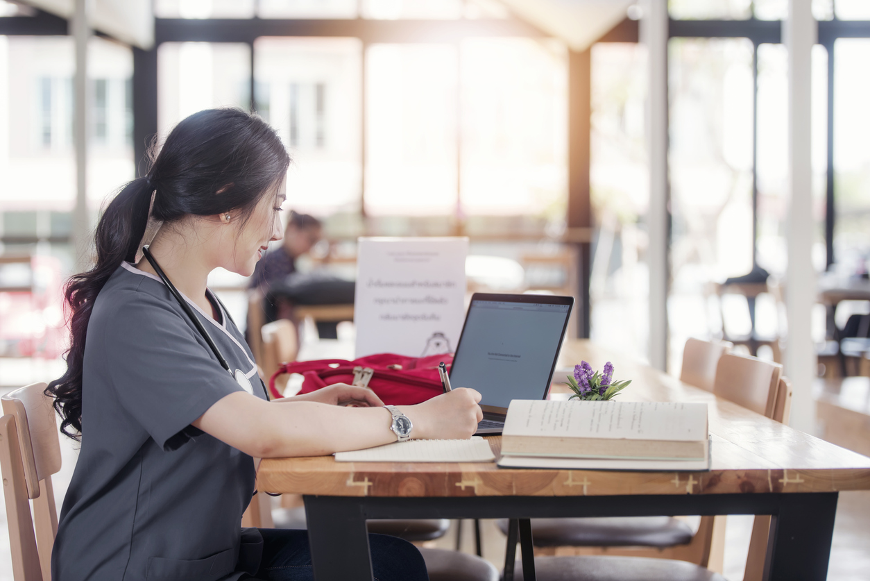 Concentrated doctor or nurse working on line with a laptop sitting in a desk in a consultation