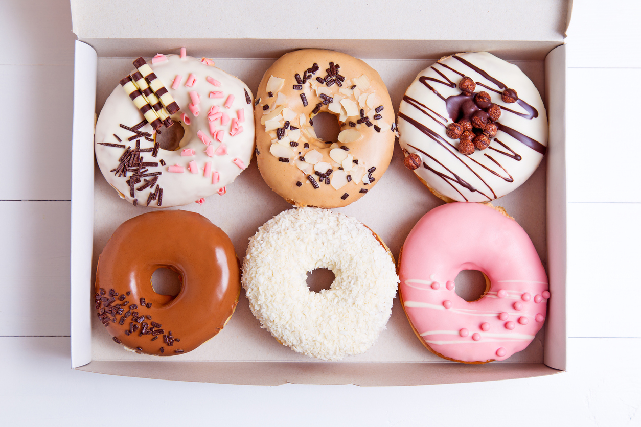 Colored donuts with glaze in a box on a white wooden background