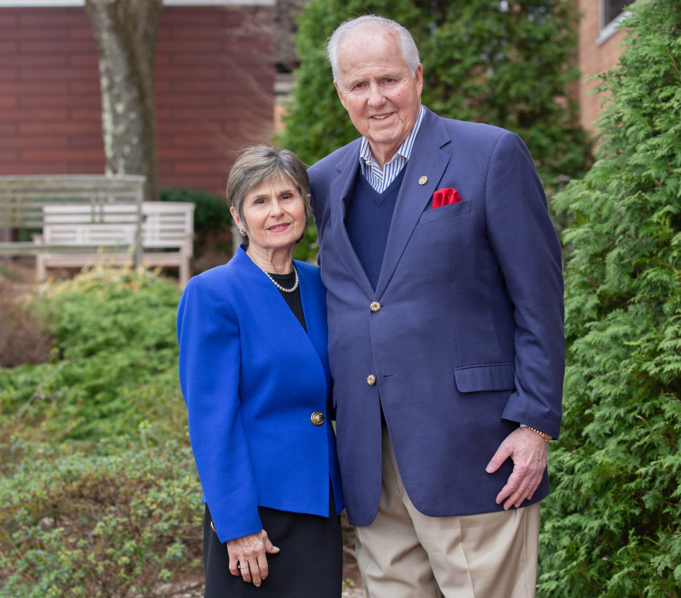 Woman in bright blue jacket standing next to a man with a navy blue suit jacket and red hankerchief