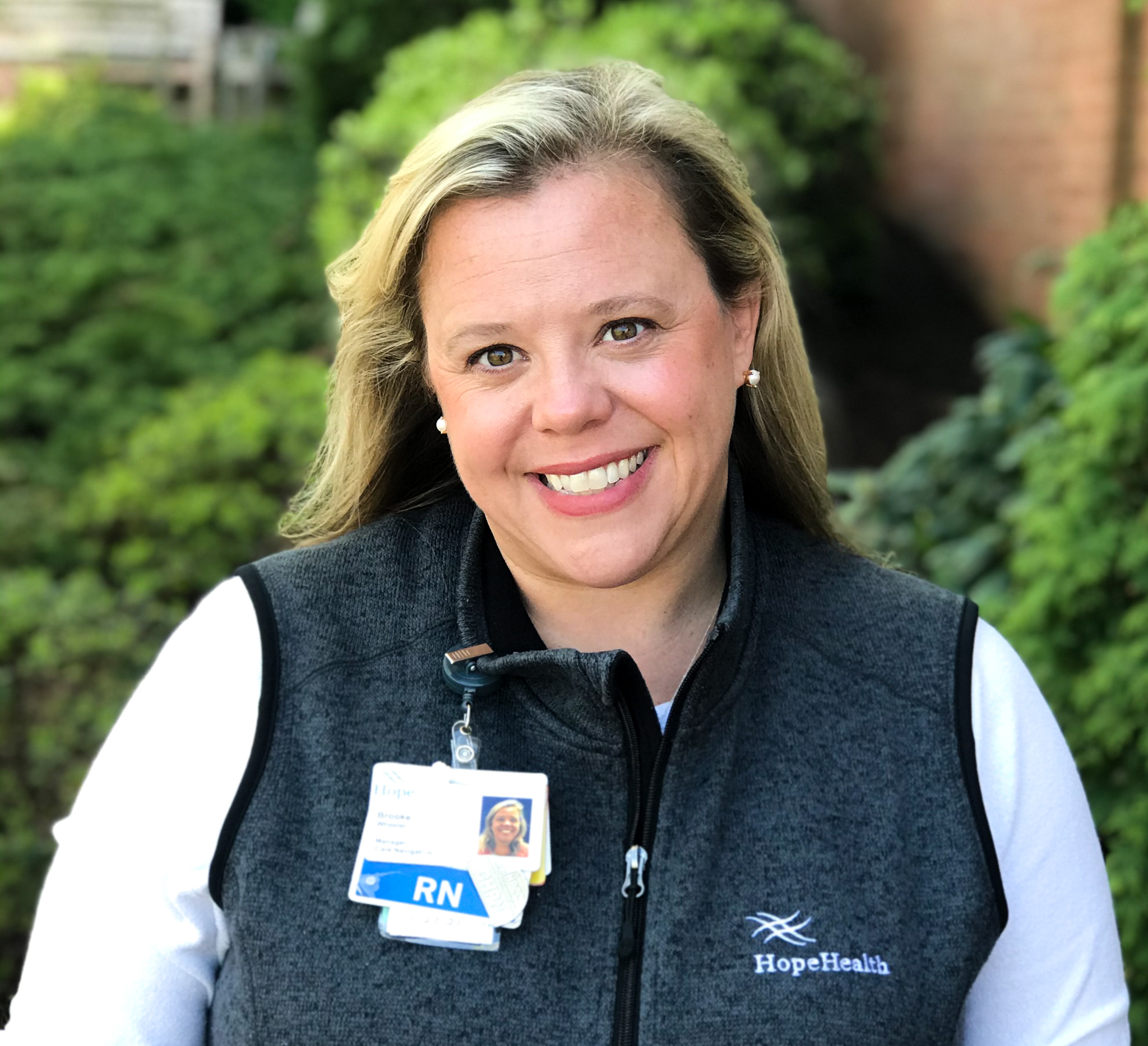 Nurse smiling in front of greenery