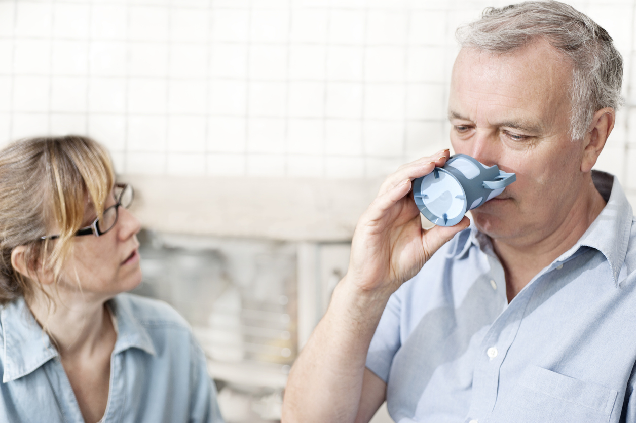 Female speech language pathologist checks male patient's swallowing while he drinks from a cup