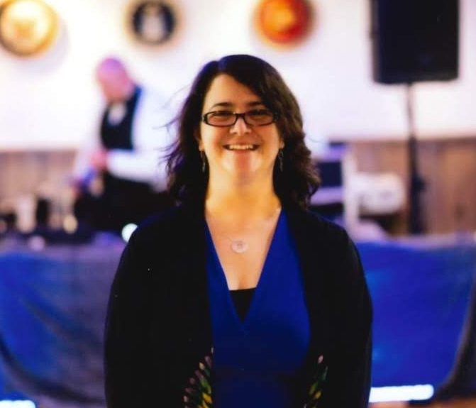 Woman wearing glasses and blue dress smiling