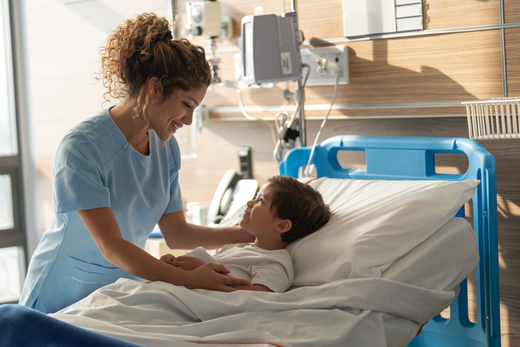 Young beautiful nurse talking to a pediatrics patient very sweetly while he smiles back Young beautiful nurse talking to a pediatrics patient very sweetly while he smiles back very happy