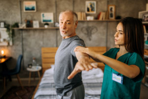 Female occupational therapist helping a male patient at home