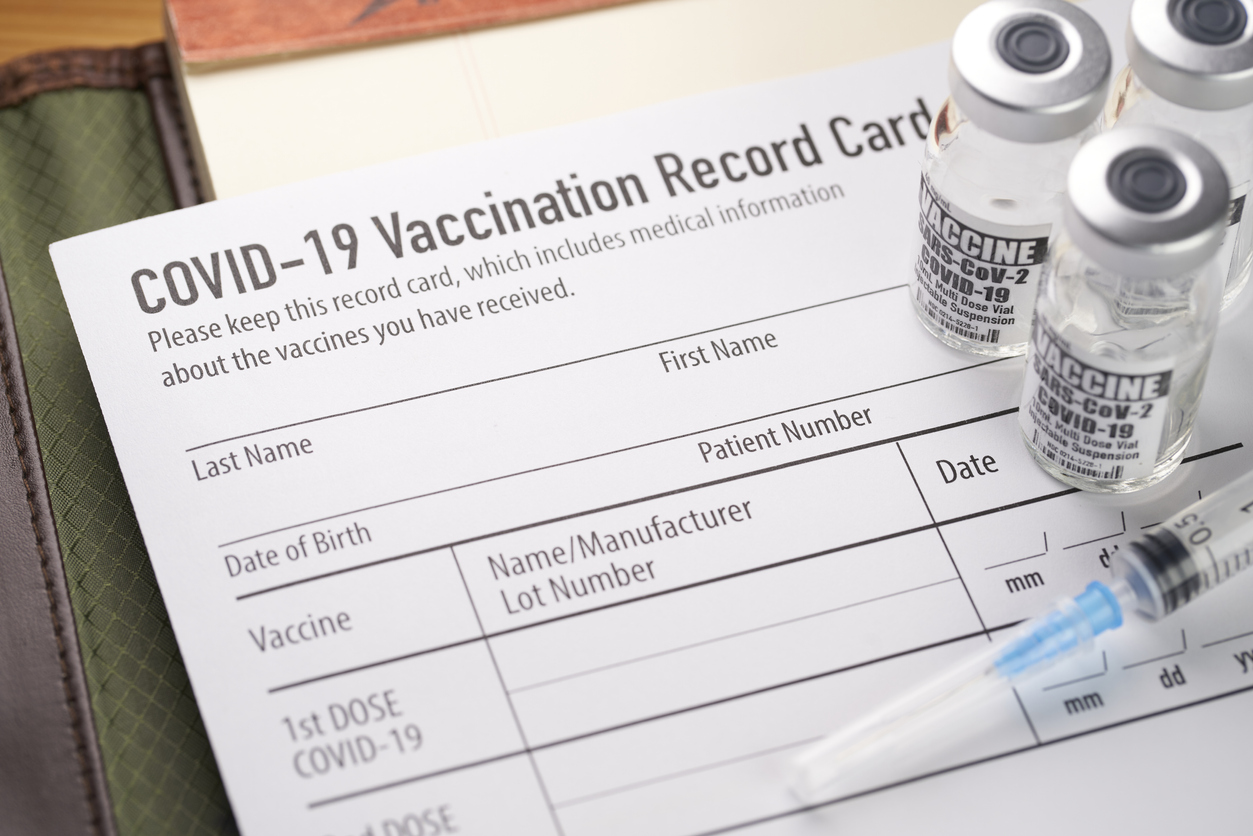 Covid-19 vaccination record card with vials and syringe.