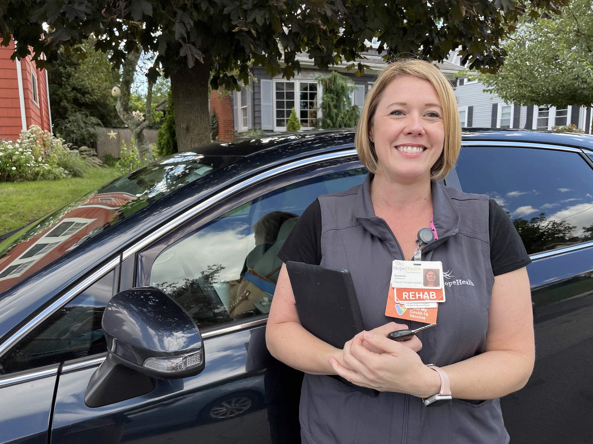 Woman in gray vest in front of SUV