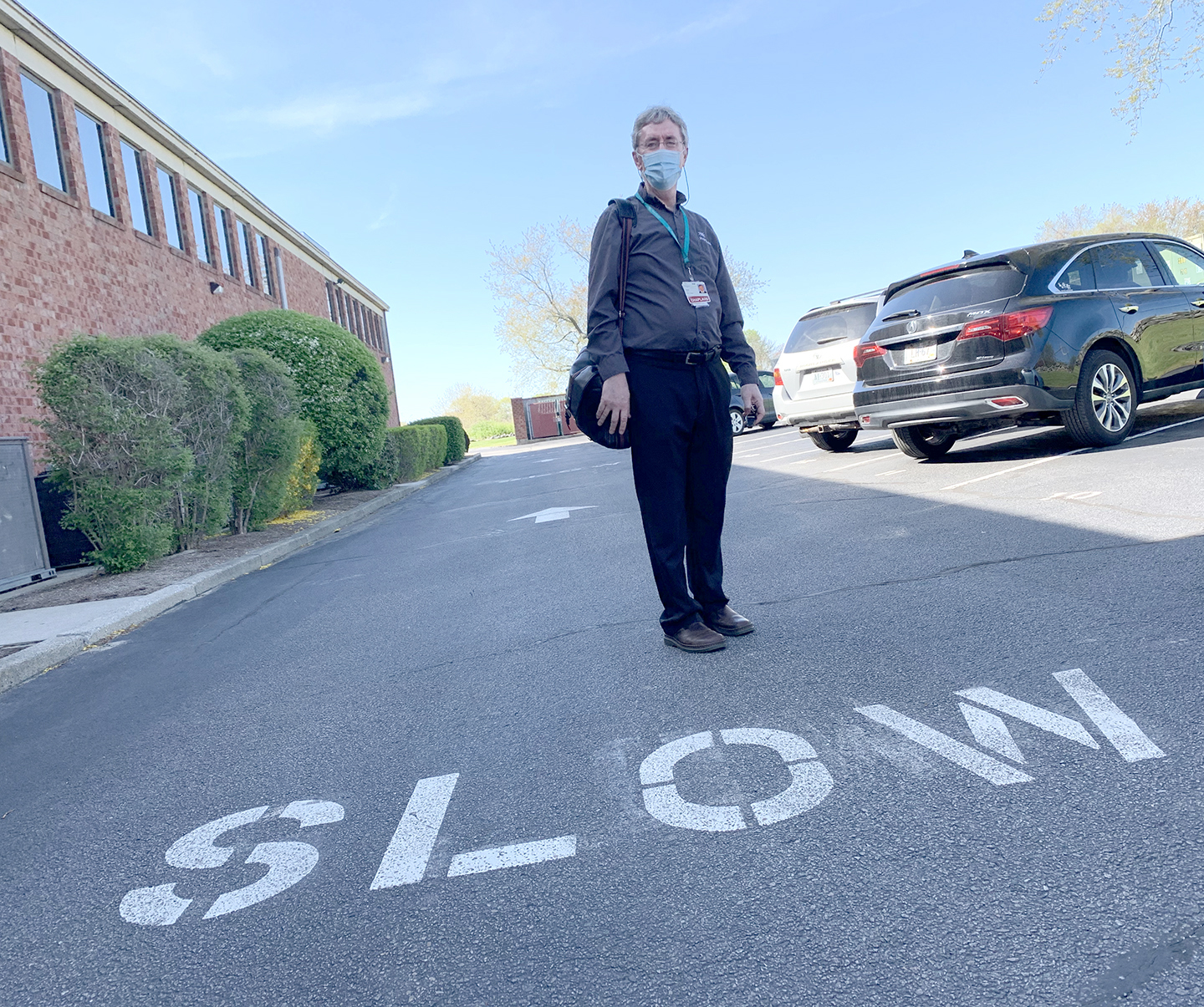 man standing on street with SLOW on pavement