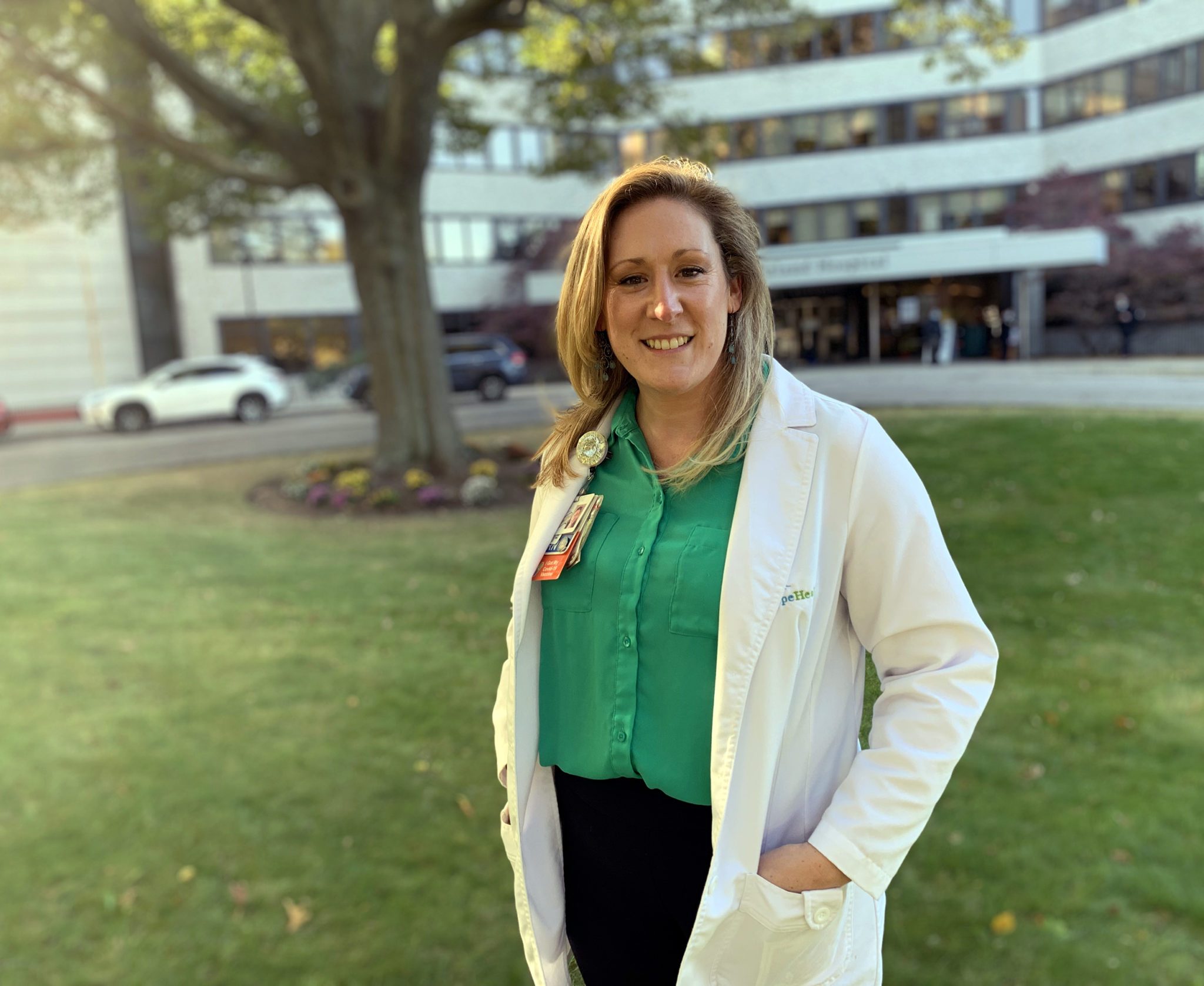 woman in white lab coat standing outside hospital
